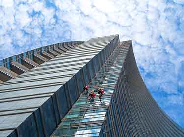 Professional window cleaners washing high-rise commercial building windows in NYC for a streak-free finish.